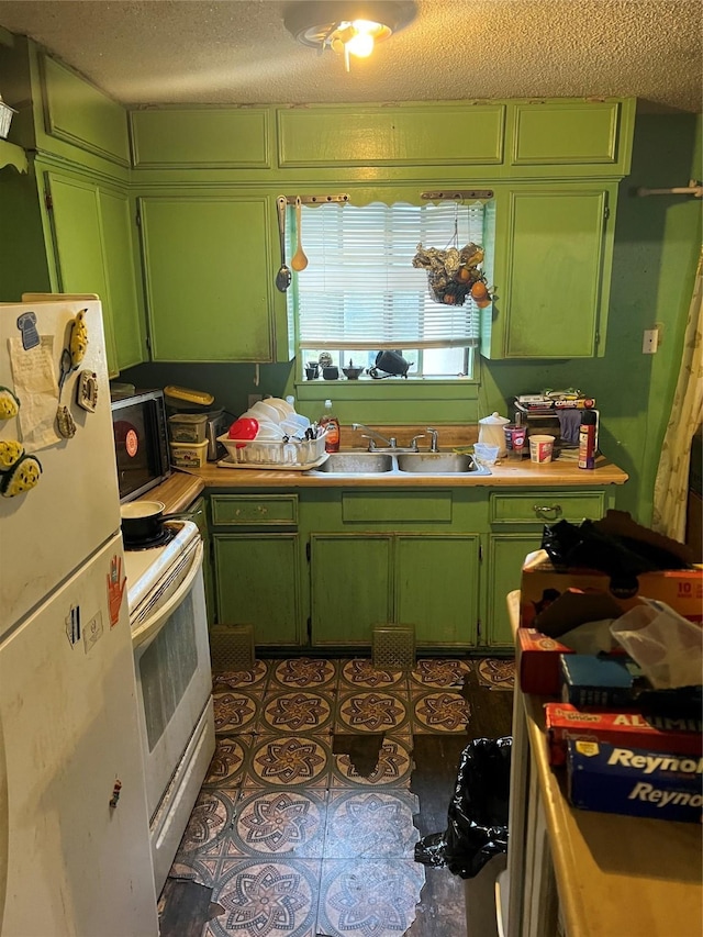 kitchen featuring sink, white appliances, and green cabinetry