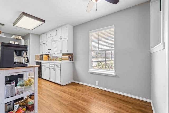 kitchen with sink, ceiling fan, light wood-type flooring, a textured ceiling, and white cabinetry