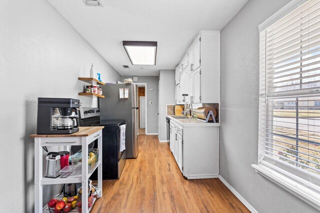 kitchen featuring white cabinets, sink, light hardwood / wood-style flooring, and stainless steel electric range