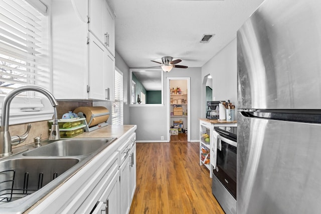 kitchen featuring hardwood / wood-style floors, sink, ceiling fan, white cabinetry, and stainless steel appliances