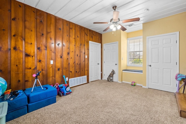 playroom with carpet, ceiling fan, and wooden walls