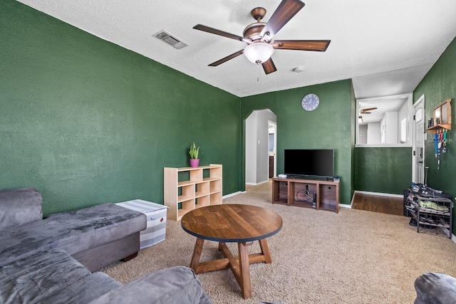 living room with ceiling fan, carpet floors, and a textured ceiling