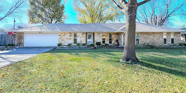 ranch-style house featuring roof with shingles, concrete driveway, a garage, stone siding, and a front lawn