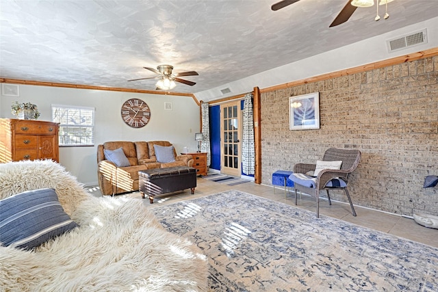 tiled bedroom featuring ceiling fan, brick wall, visible vents, and a textured ceiling