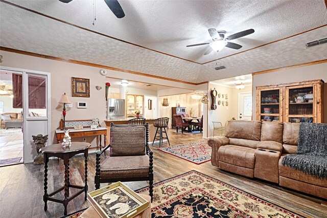 503 Mockingbird St, Bonham, TX 75418 - living area with a textured ceiling, a ceiling fan, wood finished floors, ornamental molding, and a fireplace