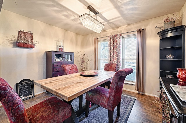 dining area featuring baseboards, hardwood / wood-style floors, and an inviting chandelier