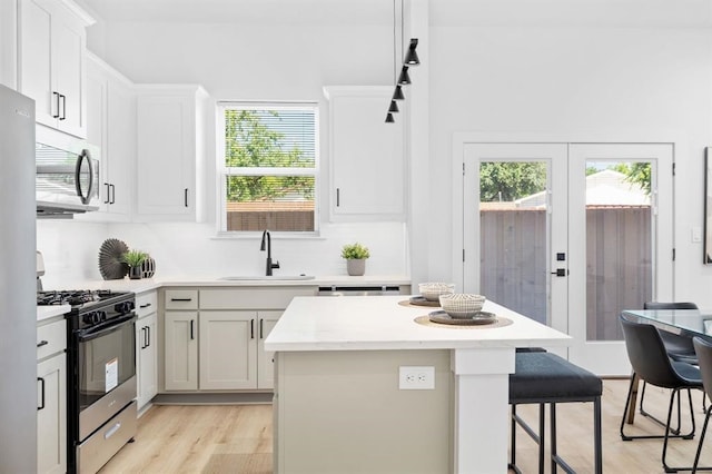 kitchen with sink, french doors, a kitchen island, white cabinets, and appliances with stainless steel finishes