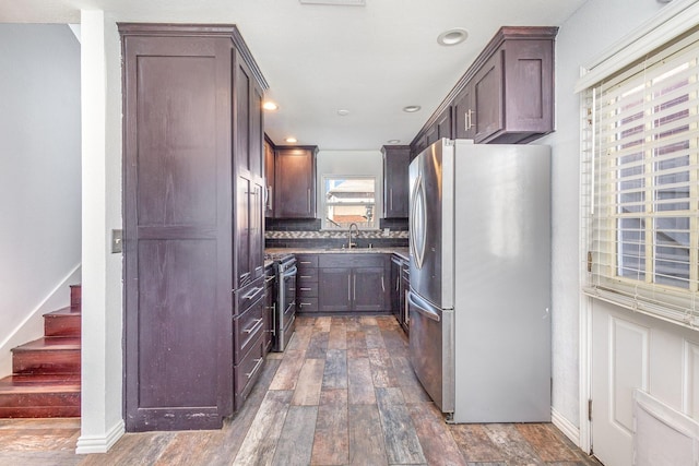 kitchen with backsplash, dark brown cabinets, stainless steel appliances, sink, and dark hardwood / wood-style floors