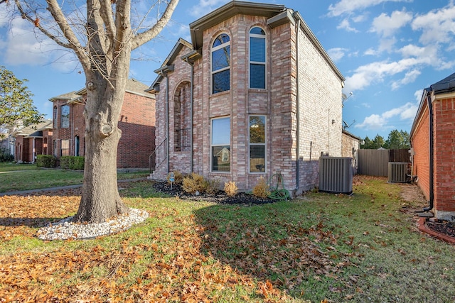 view of side of home featuring cooling unit and a yard