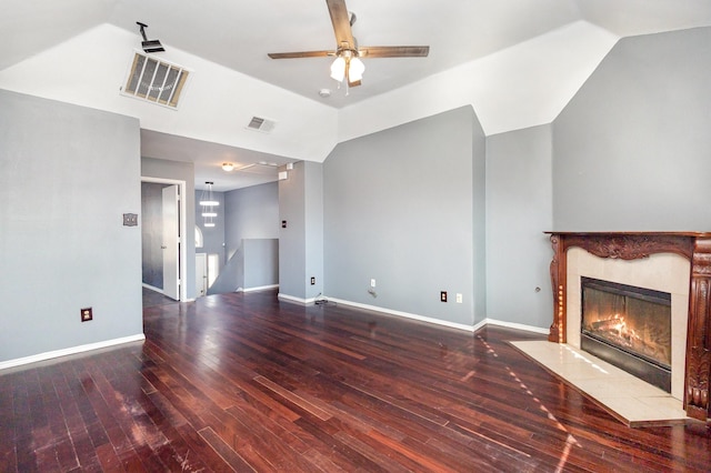 unfurnished living room with a tiled fireplace, vaulted ceiling, and hardwood / wood-style flooring