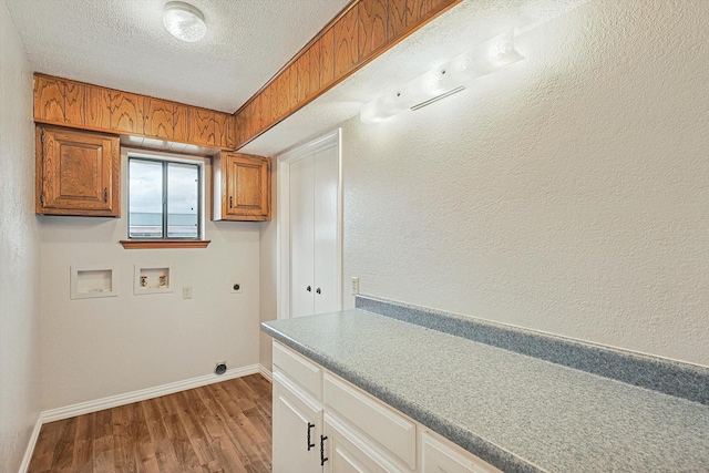 clothes washing area with cabinets, light hardwood / wood-style flooring, a textured ceiling, hookup for a washing machine, and hookup for an electric dryer