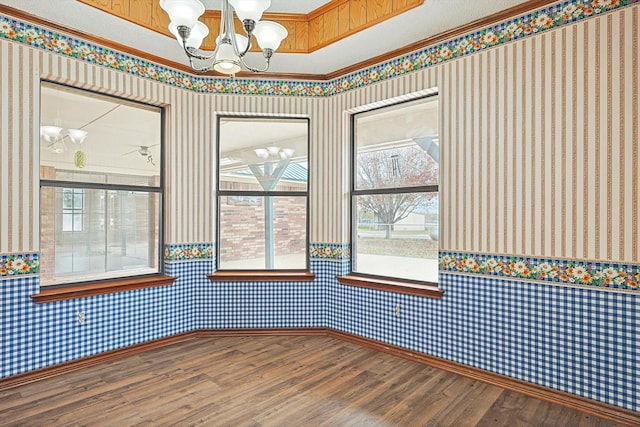 spare room with hardwood / wood-style flooring, ornamental molding, a chandelier, and a raised ceiling