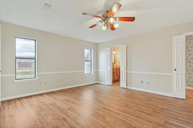 unfurnished room with ceiling fan, light hardwood / wood-style floors, and a textured ceiling