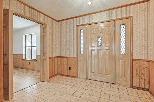 tiled foyer entrance featuring crown molding and a textured ceiling