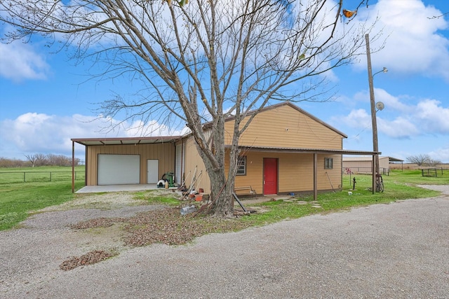 view of front of house with a garage, a carport, an outbuilding, and a front lawn