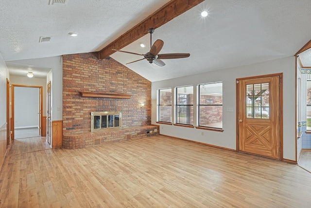 unfurnished living room featuring vaulted ceiling with beams, a fireplace, a textured ceiling, and light hardwood / wood-style flooring