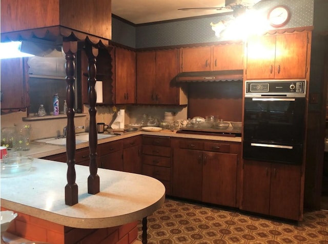 kitchen with a warming drawer, black appliances, a sink, and light countertops