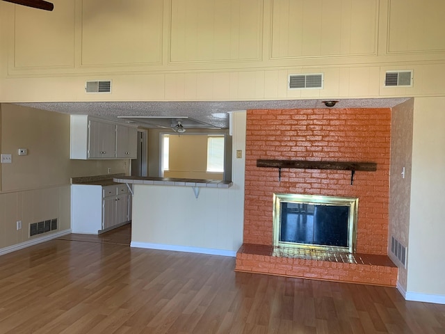 unfurnished living room featuring a fireplace, dark hardwood / wood-style floors, and ceiling fan