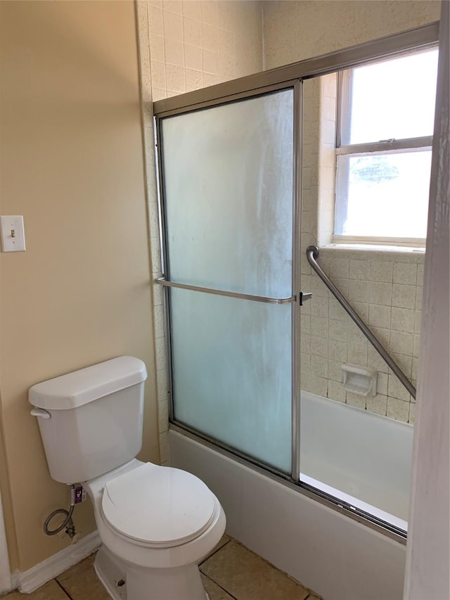 bathroom with tile patterned flooring, combined bath / shower with glass door, and toilet