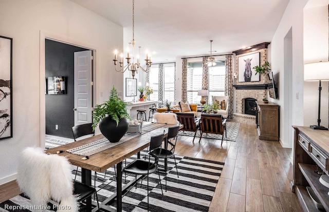 dining space with a fireplace, light hardwood / wood-style floors, and a notable chandelier