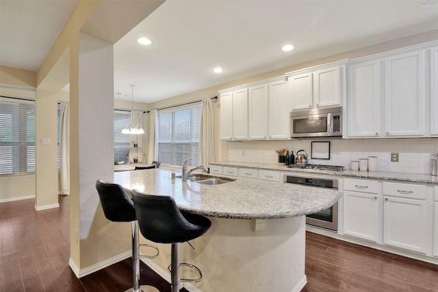 kitchen featuring hanging light fixtures, sink, white cabinets, and stainless steel appliances