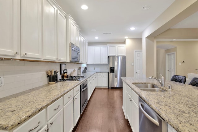 kitchen with light stone countertops, sink, white cabinetry, and stainless steel appliances