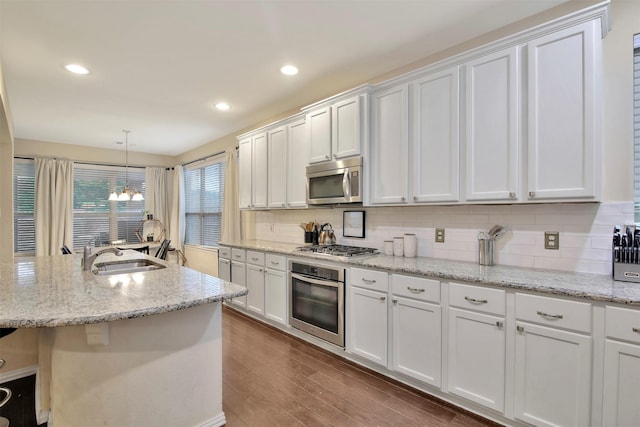 kitchen with appliances with stainless steel finishes, white cabinetry, hanging light fixtures, and sink