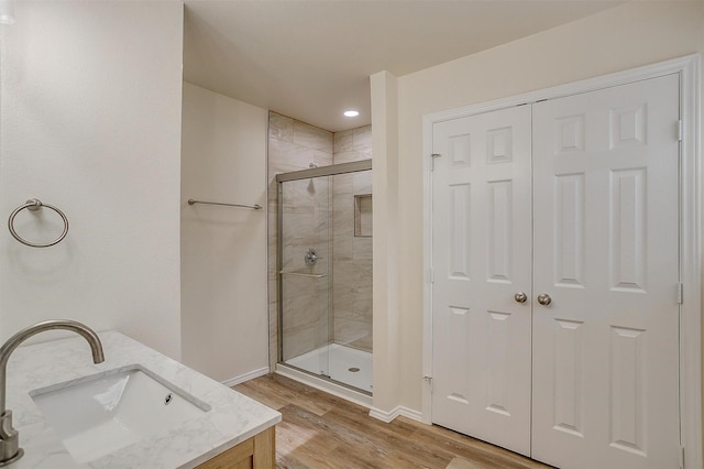 bathroom with hardwood / wood-style floors, vanity, and an enclosed shower