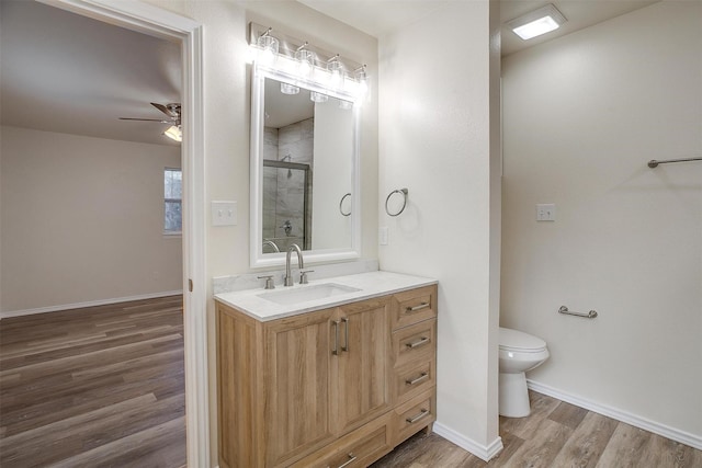 bathroom featuring ceiling fan, walk in shower, toilet, vanity, and hardwood / wood-style flooring