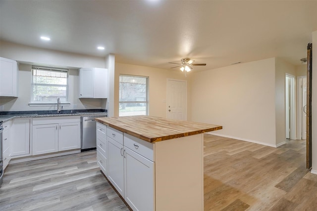 kitchen featuring white cabinetry, sink, wooden counters, stainless steel dishwasher, and a kitchen island