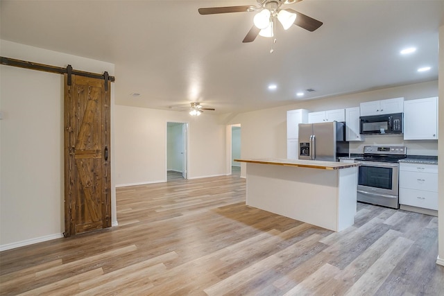 kitchen featuring stainless steel appliances, a kitchen island, a barn door, light hardwood / wood-style floors, and white cabinetry