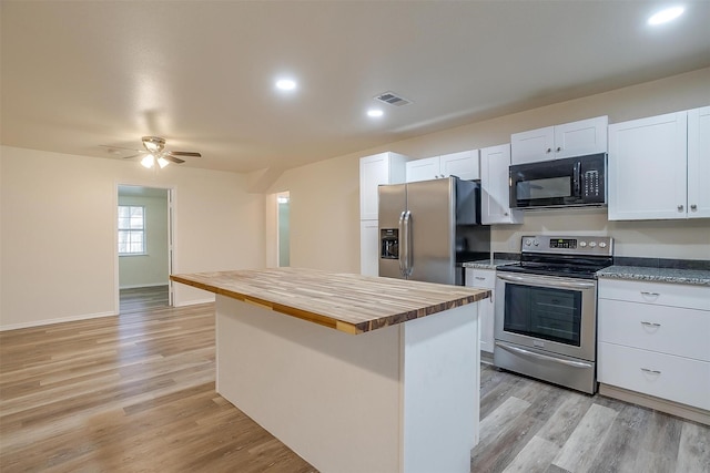 kitchen featuring light wood-type flooring, stainless steel appliances, white cabinets, a kitchen island, and butcher block counters