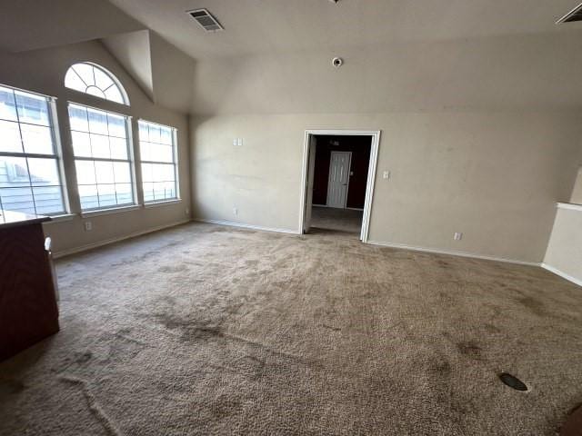 carpeted empty room with vaulted ceiling