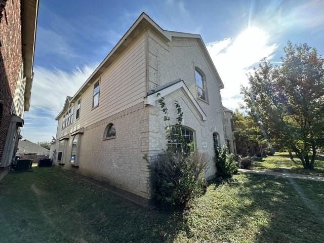 view of side of home with central air condition unit and a yard