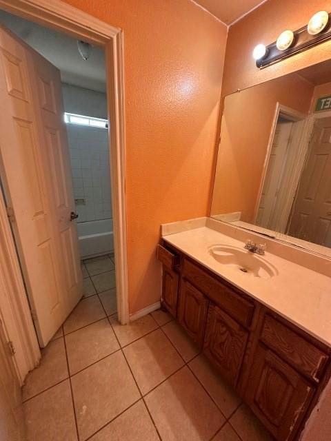 bathroom with tile patterned floors, vanity, and tiled shower / bath