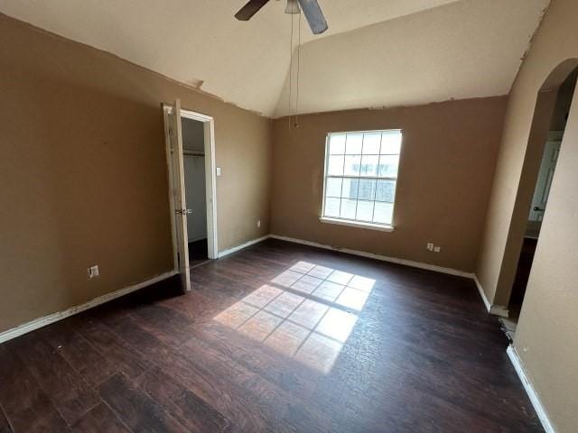 unfurnished bedroom with ceiling fan, dark hardwood / wood-style floors, and vaulted ceiling