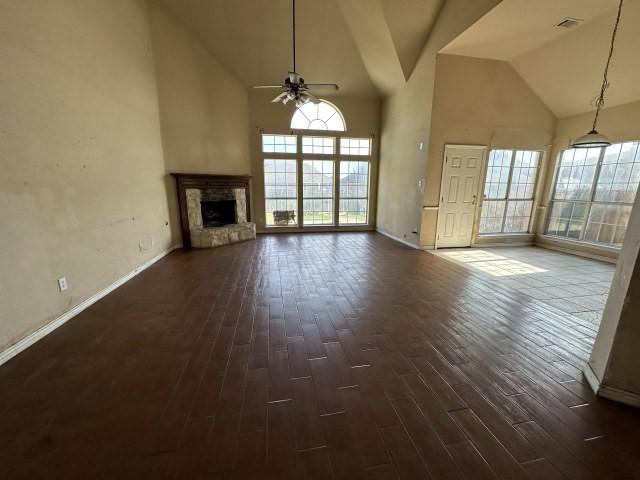 unfurnished living room with ceiling fan, dark hardwood / wood-style flooring, and a towering ceiling