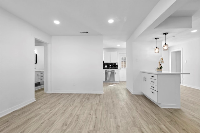 kitchen with stainless steel dishwasher, backsplash, pendant lighting, white cabinets, and light wood-type flooring