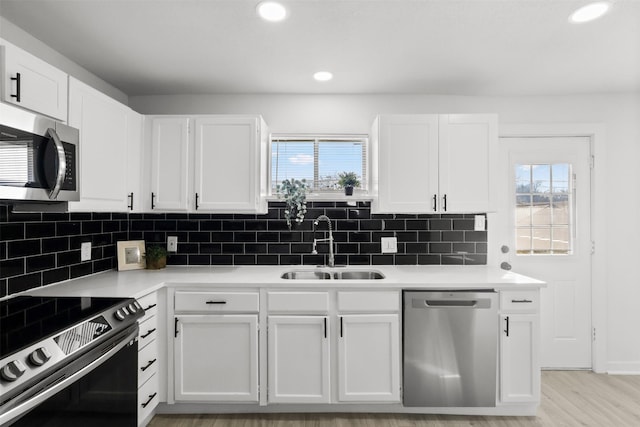 kitchen featuring stainless steel appliances, white cabinetry, and sink