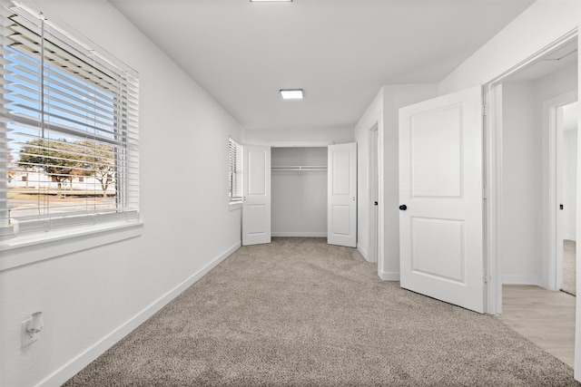 unfurnished bedroom featuring light colored carpet and a closet