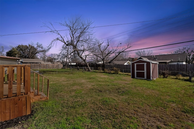 yard at dusk featuring a storage shed and a wooden deck