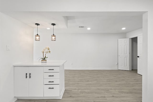 bar with decorative light fixtures, light wood-type flooring, and white cabinetry