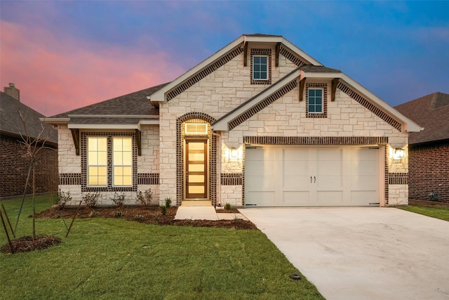 view of front of house with driveway, stone siding, roof with shingles, an attached garage, and a front yard