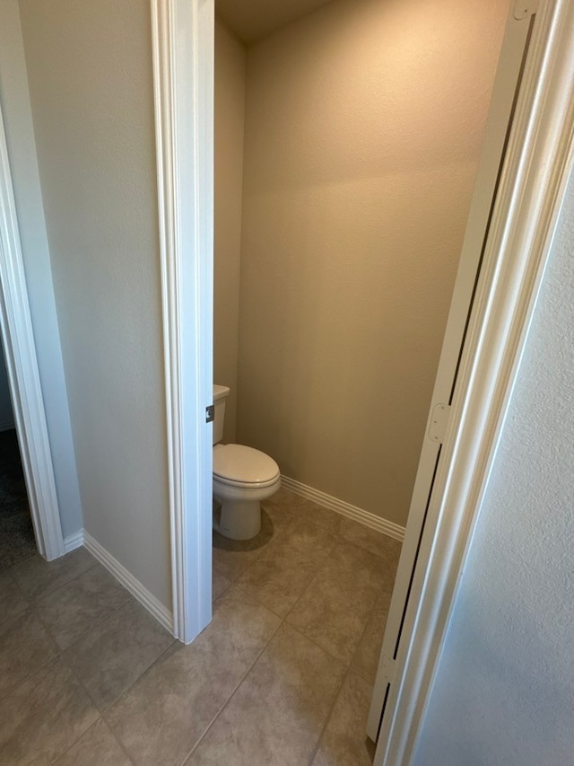 bathroom featuring toilet, tile patterned flooring, and baseboards