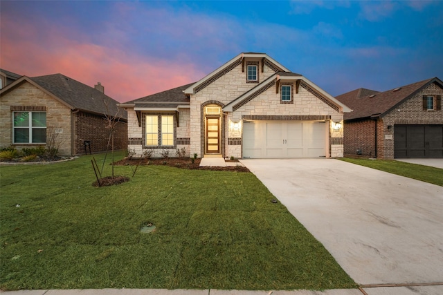 view of front of house featuring concrete driveway, a garage, stone siding, and a yard