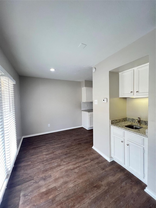 interior space featuring light stone countertops, dark hardwood / wood-style flooring, white cabinetry, and sink