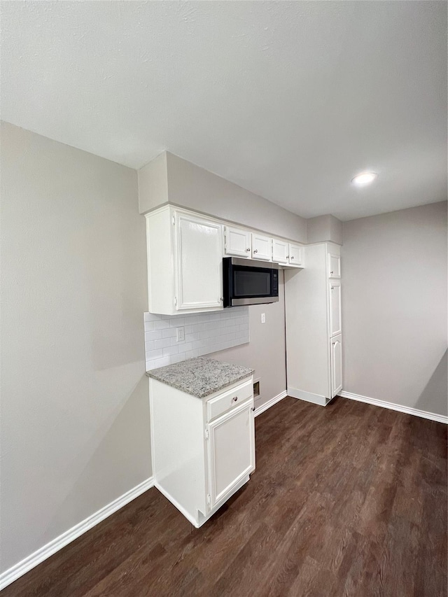 kitchen with white cabinets, dark hardwood / wood-style floors, light stone countertops, and tasteful backsplash