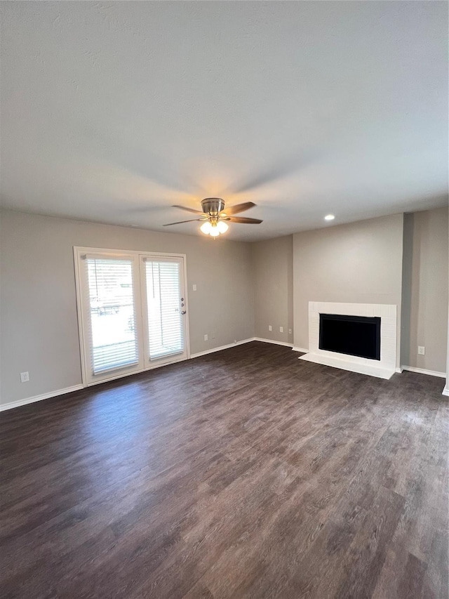 unfurnished living room featuring ceiling fan, a fireplace, and dark wood-type flooring