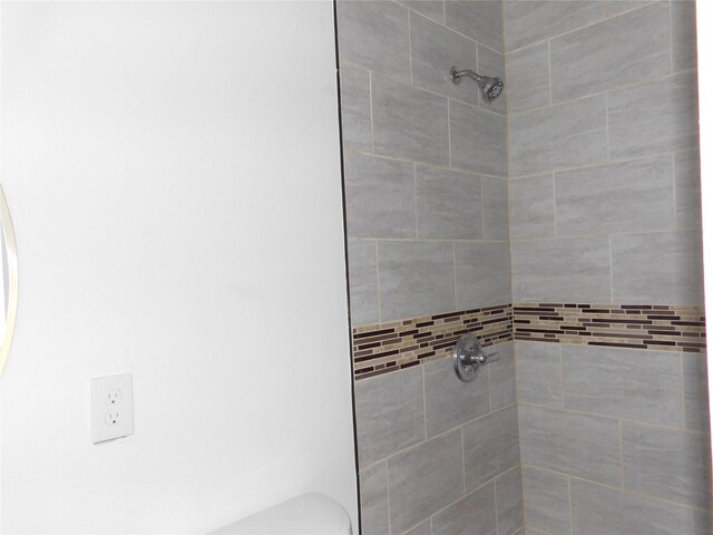 bathroom featuring a tile shower and toilet