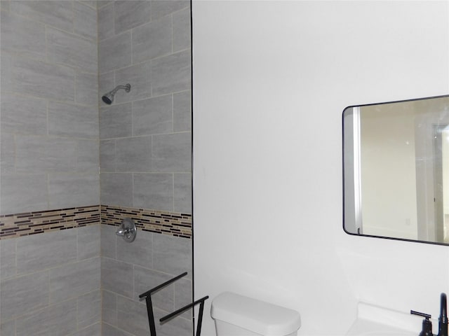 bathroom featuring tiled shower and toilet